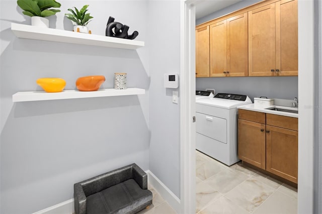 laundry room featuring washing machine and clothes dryer, cabinet space, baseboards, and a sink