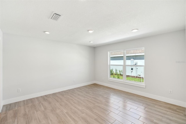 unfurnished room with visible vents, recessed lighting, light wood-type flooring, and baseboards