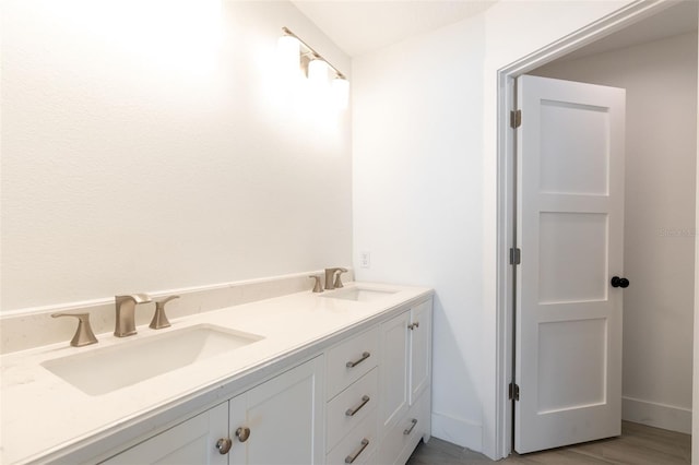 bathroom featuring a sink, baseboards, and double vanity