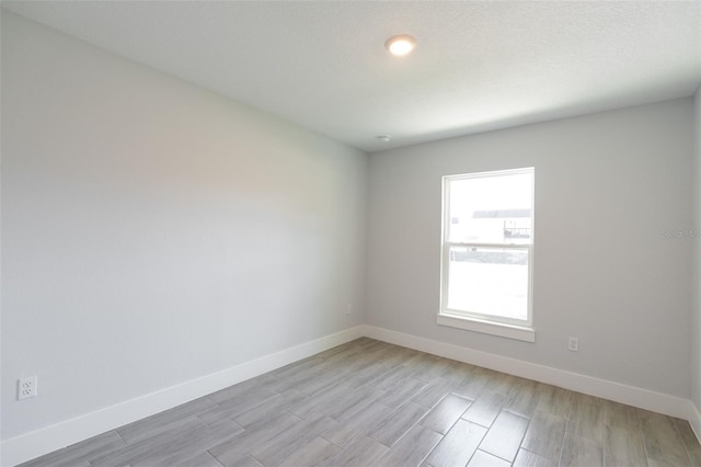 spare room with light wood-style flooring and baseboards