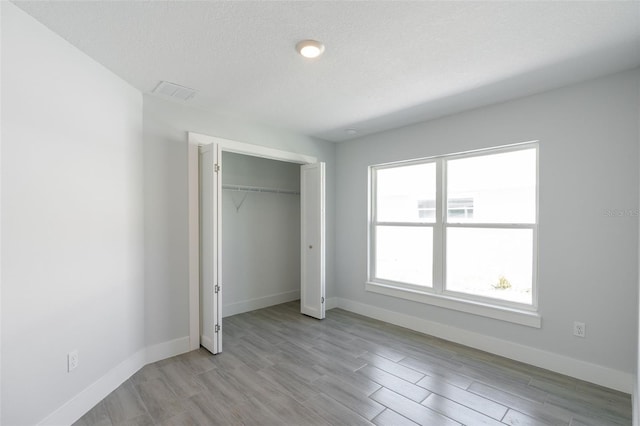 unfurnished bedroom featuring visible vents, light wood-type flooring, and baseboards