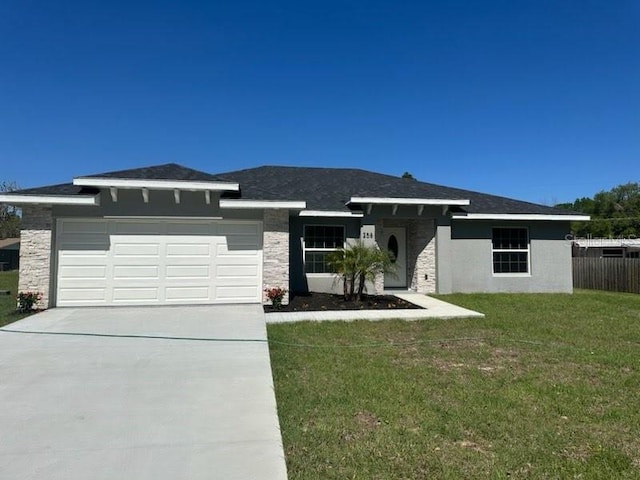 prairie-style house with a front yard, fence, stucco siding, concrete driveway, and a garage