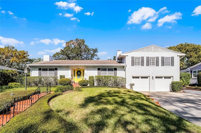 split level home featuring driveway, fence, a front yard, a garage, and a chimney