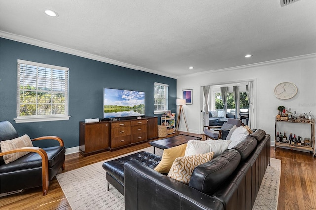 living area with plenty of natural light, wood finished floors, and ornamental molding