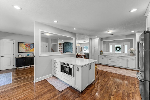 kitchen featuring a peninsula, light countertops, freestanding refrigerator, and dark wood-style flooring