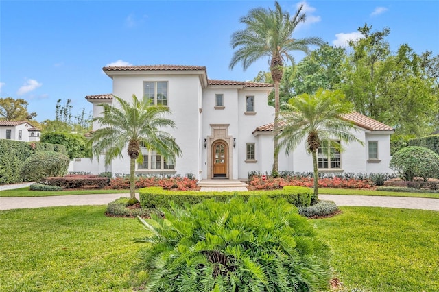 mediterranean / spanish home with a front yard, a tile roof, and driveway