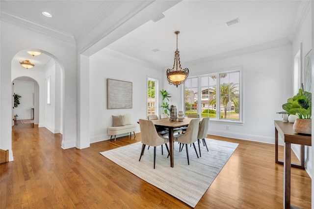 dining room featuring ornamental molding, wood finished floors, recessed lighting, arched walkways, and baseboards