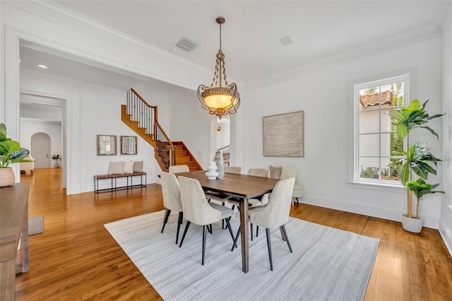 dining room featuring arched walkways, visible vents, crown molding, and stairs