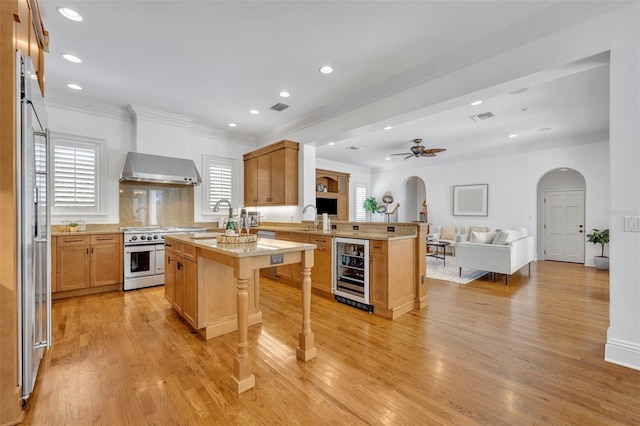 kitchen featuring open floor plan, wine cooler, arched walkways, appliances with stainless steel finishes, and a peninsula