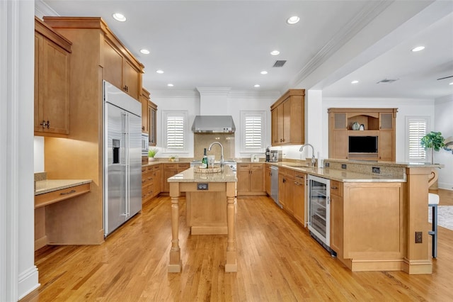 kitchen featuring beverage cooler, a sink, light stone counters, a kitchen breakfast bar, and appliances with stainless steel finishes