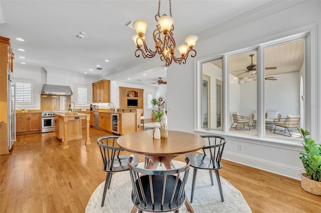 dining room with beverage cooler, baseboards, light wood-style flooring, ceiling fan, and crown molding