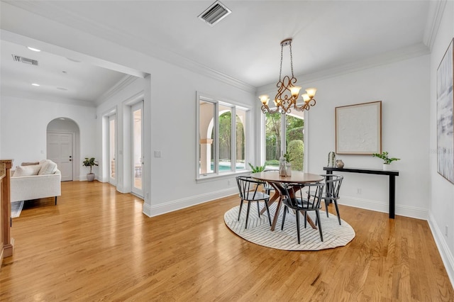 dining room with visible vents, light wood finished floors, arched walkways, ornamental molding, and a notable chandelier