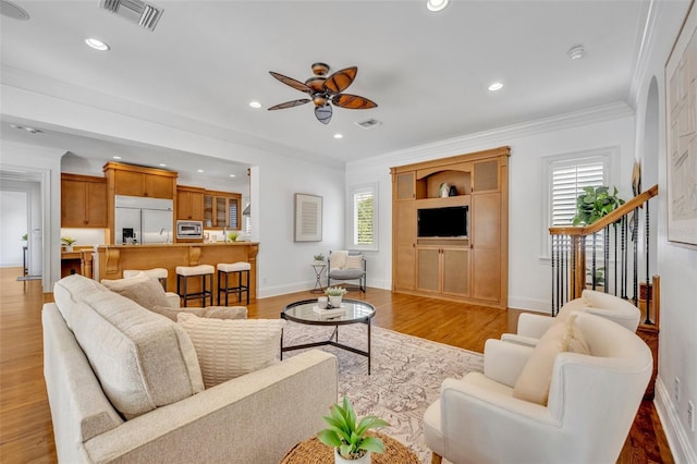 living area with visible vents, recessed lighting, light wood-style floors, and ornamental molding