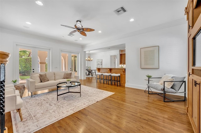 living room with light wood-style flooring, french doors, visible vents, and ornamental molding