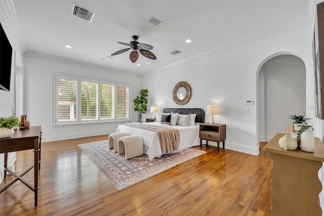 bedroom with visible vents, crown molding, baseboards, and wood finished floors