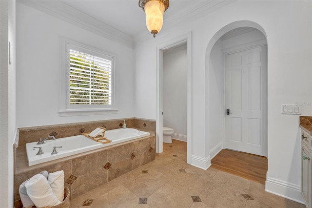 bathroom with crown molding, baseboards, toilet, a garden tub, and vanity