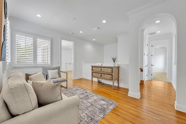 living room featuring arched walkways, recessed lighting, light wood finished floors, and crown molding