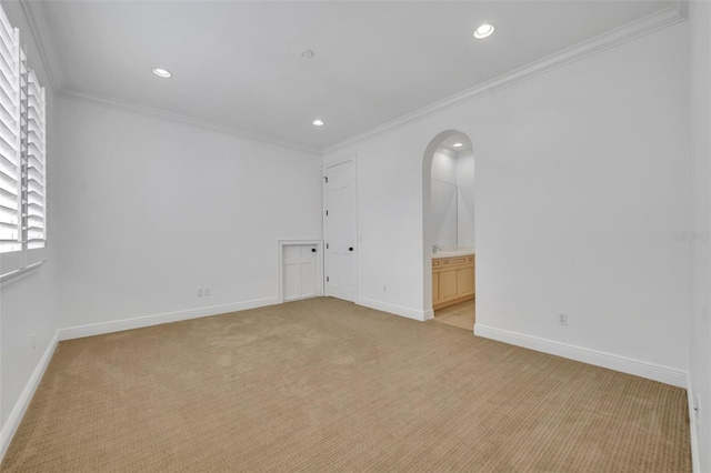 unfurnished room featuring baseboards, ornamental molding, light carpet, recessed lighting, and arched walkways