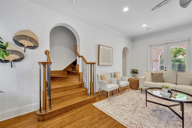 living area featuring ornamental molding, wood finished floors, recessed lighting, arched walkways, and stairs