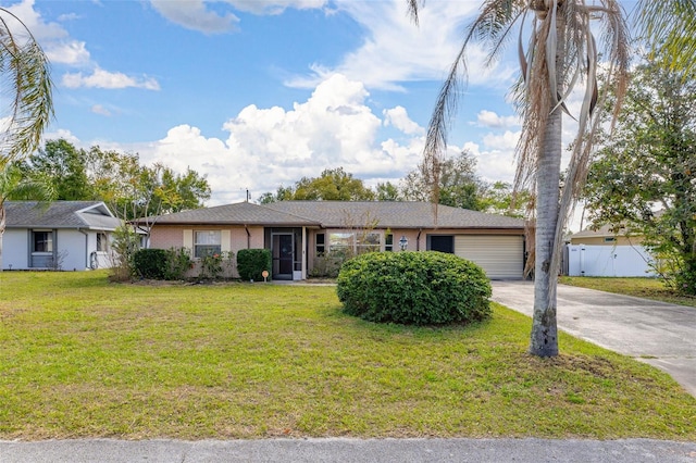 single story home featuring a front yard, concrete driveway, an attached garage, and fence