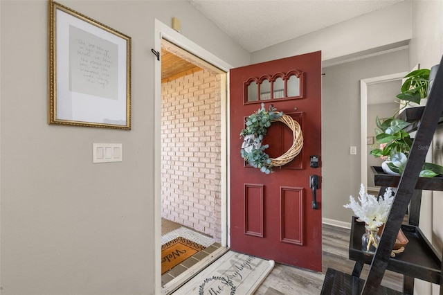 entrance foyer with baseboards, a textured ceiling, and wood finished floors