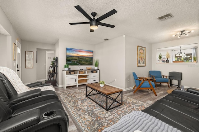 living room featuring visible vents, wood finished floors, and a ceiling fan