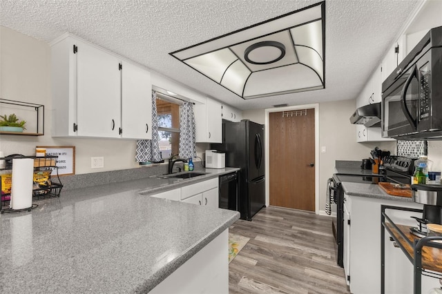 kitchen featuring under cabinet range hood, light wood-type flooring, white cabinets, black appliances, and a sink