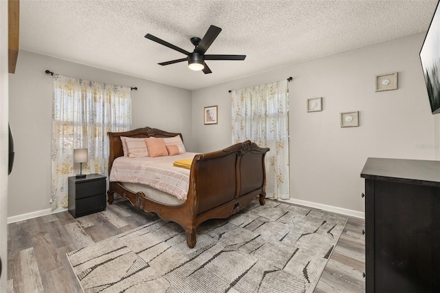 bedroom with a textured ceiling, a ceiling fan, baseboards, and wood finished floors