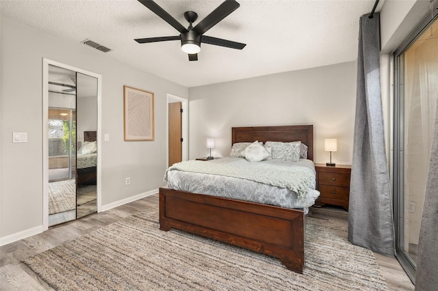 bedroom with baseboards, visible vents, light wood-type flooring, and a textured ceiling