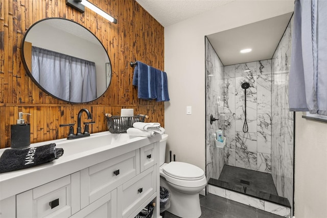 full bathroom featuring vanity, a marble finish shower, wood walls, a textured ceiling, and toilet