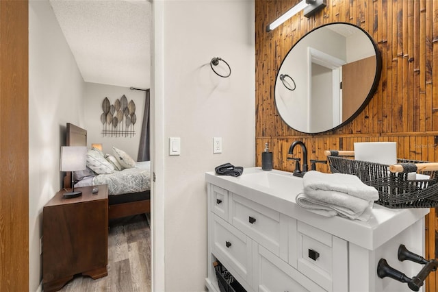 bathroom featuring ensuite bathroom, a textured ceiling, wood finished floors, wood walls, and vanity