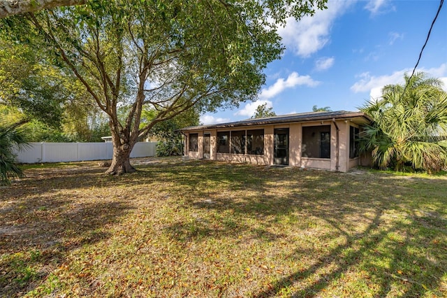 back of property with a yard, stucco siding, and fence