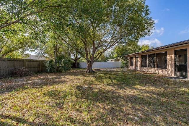 view of yard featuring a fenced backyard and a sunroom