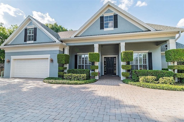 view of front of home featuring stucco siding, decorative driveway, and a garage