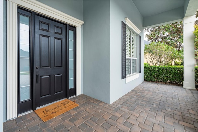 view of exterior entry with a porch and stucco siding