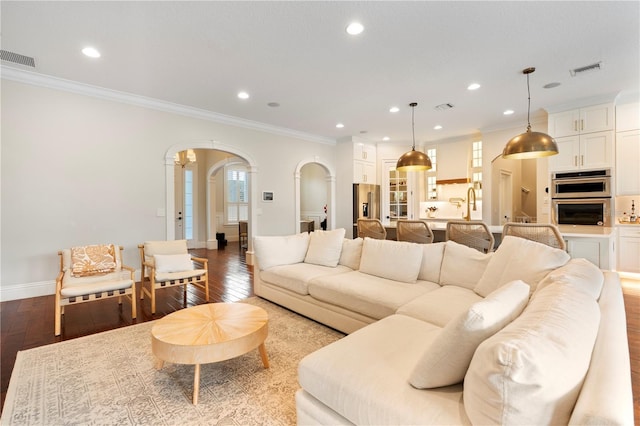 living area featuring recessed lighting, arched walkways, light wood-style floors, and crown molding