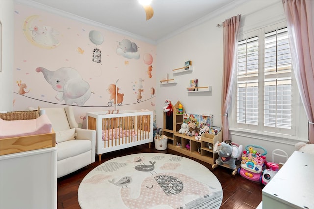 bedroom featuring a crib, wood finished floors, and crown molding