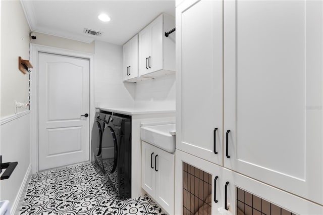 washroom with light tile patterned floors, visible vents, cabinet space, a sink, and independent washer and dryer