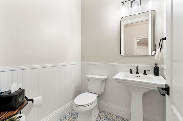 bathroom featuring a wainscoted wall and toilet