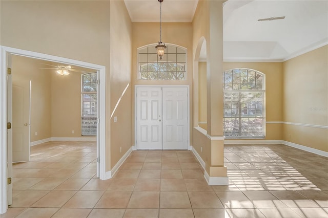 foyer featuring a ceiling fan, light tile patterned flooring, baseboards, and arched walkways