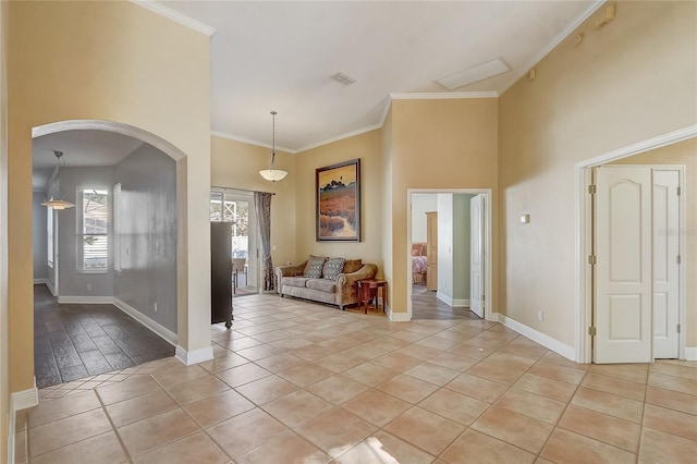 entrance foyer featuring light tile patterned flooring, baseboards, arched walkways, and ornamental molding