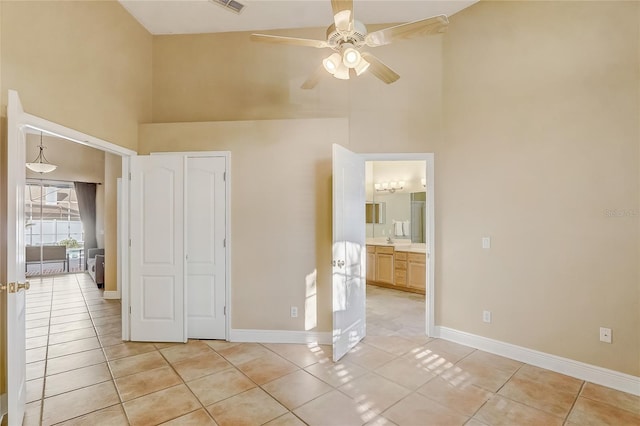 unfurnished bedroom with baseboards, light tile patterned flooring, and a towering ceiling