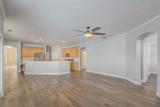 unfurnished living room featuring visible vents, wood finished floors, arched walkways, baseboards, and ceiling fan