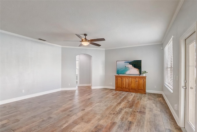 unfurnished living room featuring arched walkways, visible vents, a healthy amount of sunlight, and light wood-type flooring