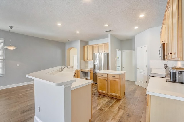 kitchen featuring visible vents, arched walkways, a large island with sink, stainless steel appliances, and light wood-type flooring