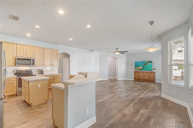 kitchen with light brown cabinetry, tasteful backsplash, a center island, stainless steel appliances, and arched walkways