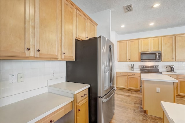 kitchen featuring light brown cabinetry, visible vents, stainless steel appliances, and light countertops