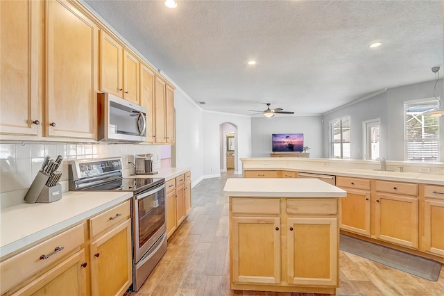 kitchen featuring ceiling fan, light brown cabinetry, arched walkways, stainless steel appliances, and a sink