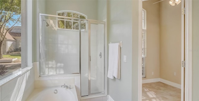 bathroom featuring baseboards, plenty of natural light, a stall shower, and a washtub