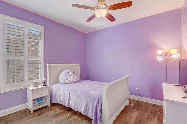 bedroom with ceiling fan, baseboards, and wood finished floors